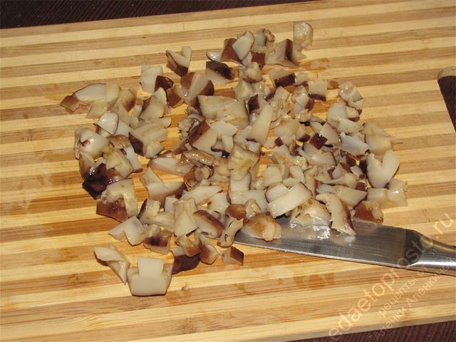 Измельчить подготовленные грибы на разделочной доске, пошаговое фото приготовления салата с солеными грибами