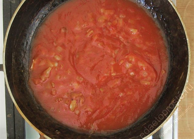 К обжаренному луку добавить немного воды и томатную пасту