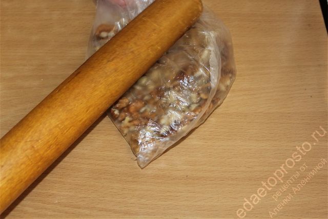Очищенные грецкие орехи измельчить при помощи пакета и скалки