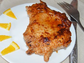 вкусные стейки из свинины на тарелке с ломтиками апельсина
