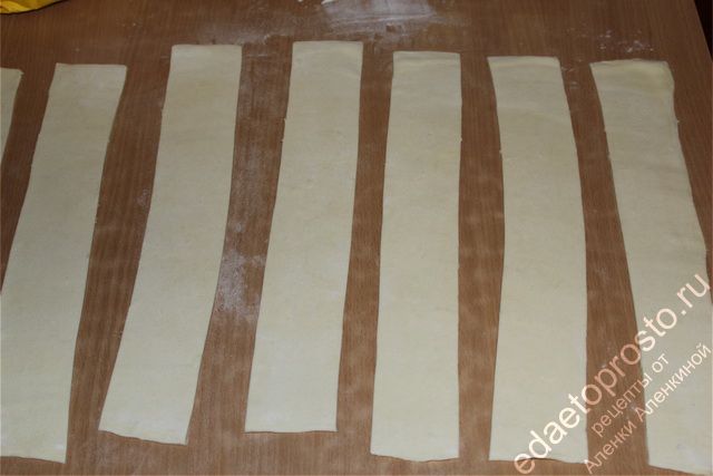 слоеное тесто нарезать длинными полосками шириной 4-5 см