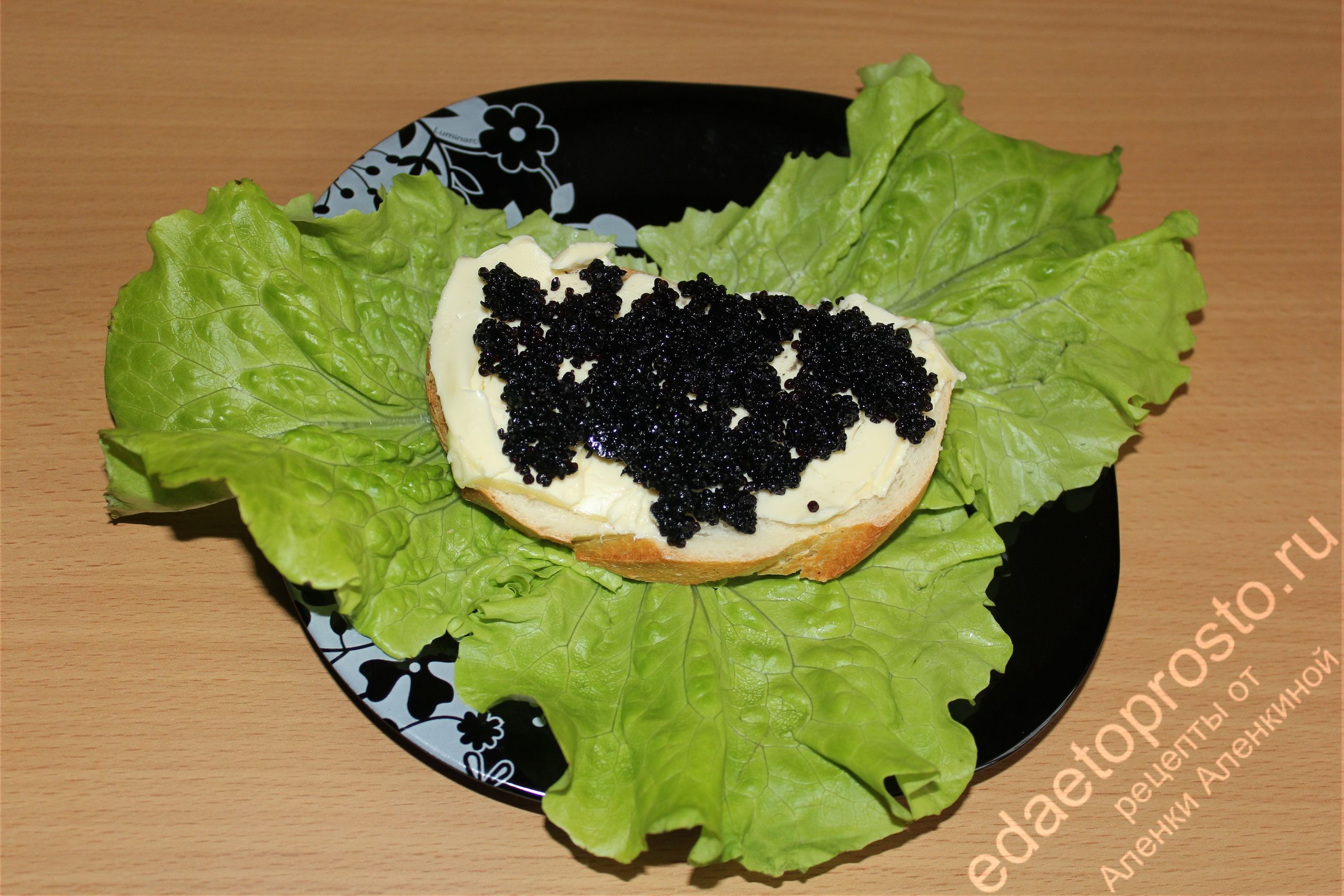 на фото бутерброд с черной икрой на листьях салата