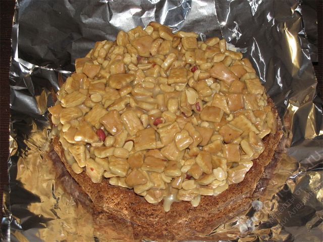 Выложить равномерно по поверхности коржа всю начинку. пошаговое фото приготовления торта Сникерс