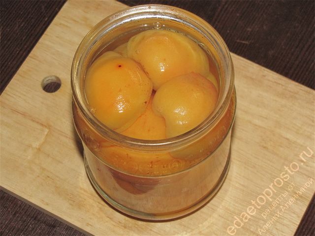 Залить горячий сироп в банку с абрикосами