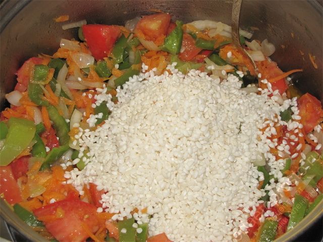 Слить с риса полностью воду и добавить его в кастрюлю с овощами
