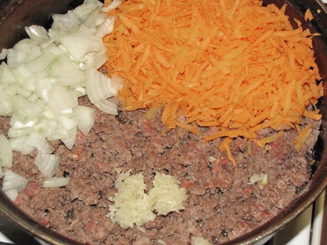 Добавить в сковороду к обжаренному фаршу подготовленные морковь овощи